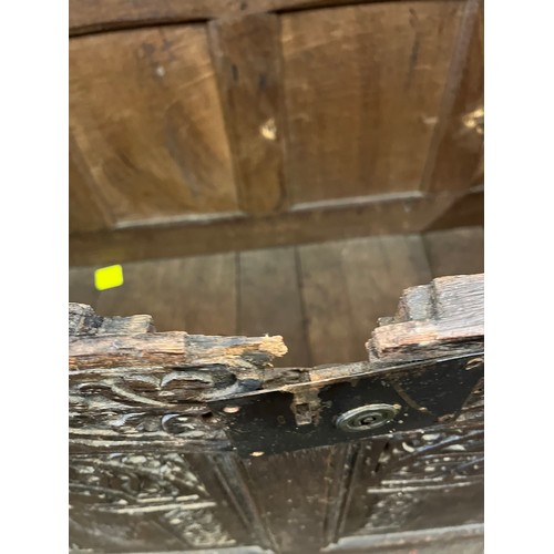 309 - An antique coffer, carved to the front. Later addition of casters. Note damage around lock.