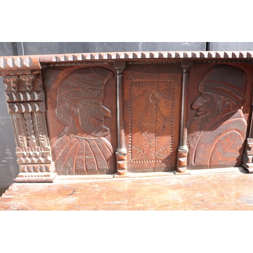 410 - Carved oak continental bookcase with raised back, decorated with Caricatures measuring approx 111cm ... 