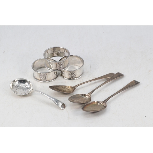 24 - Three silver hallmarked napkin rings embossed to front the 12 club together with a silver tea strain... 