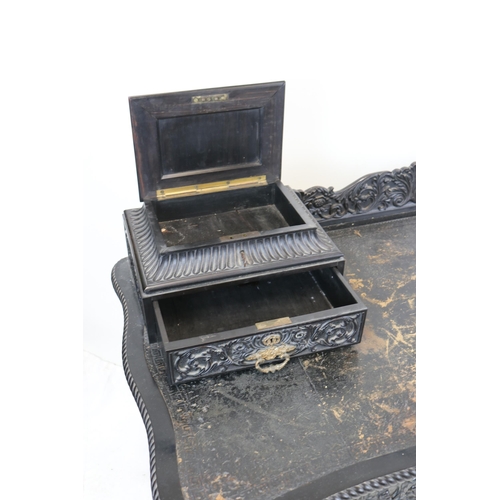 110 - Ornate ebonised desk with carved raised back, two raised drawers with coromandel lidded compartments... 