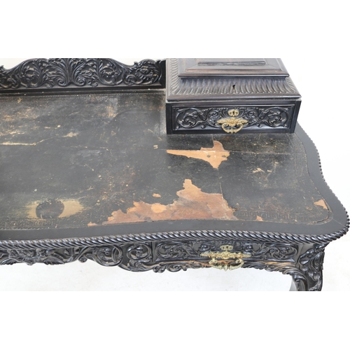 110 - Ornate ebonised desk with carved raised back, two raised drawers with coromandel lidded compartments... 