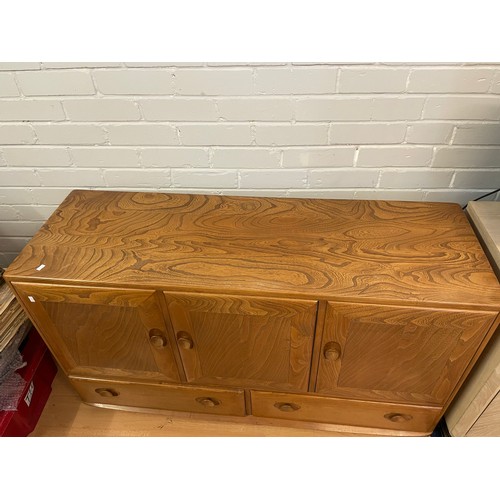 576 - An Ercol Windsor sideboard three cupboard doors over two drawers on castors (measures approx. W130cm... 