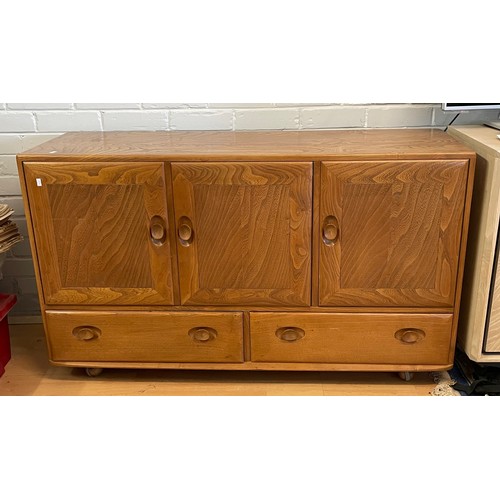 576 - An Ercol Windsor sideboard three cupboard doors over two drawers on castors (measures approx. W130cm... 