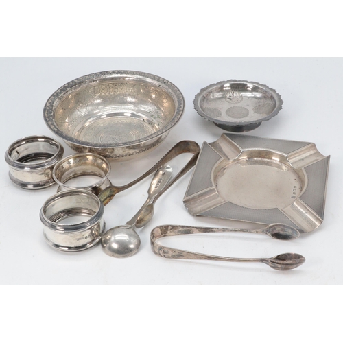 10 - 3 silver napkin rings, two silver sugar tongs, silver mustard spoon, engine turned ashtray, two east... 