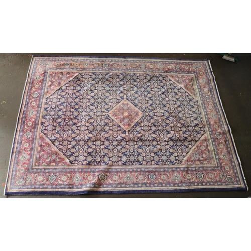 426 - A large rug with a blue ground, made in Iran, measuring approx. 305w x 399cml