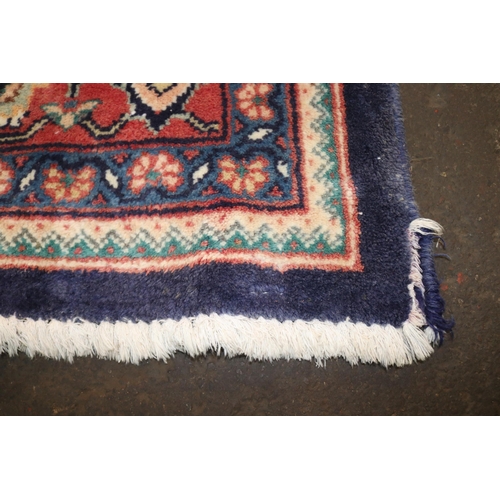 426 - A large rug with a blue ground, made in Iran, measuring approx. 305w x 399cml