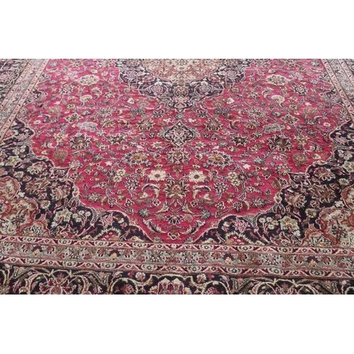 427 - A large rug with a red ground, made in Iran measuring approx. 298w x 386cmd