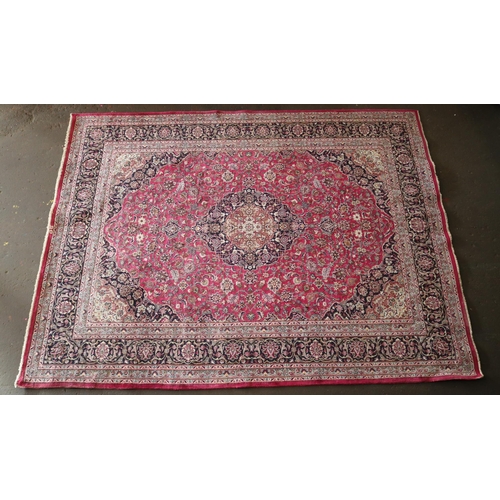 427 - A large rug with a red ground, made in Iran measuring approx. 298w x 386cmd