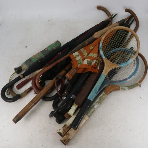 129 - A collection of walking sticks, umbrellas, parasols and tennis rackets. Some of the sticks have gold... 