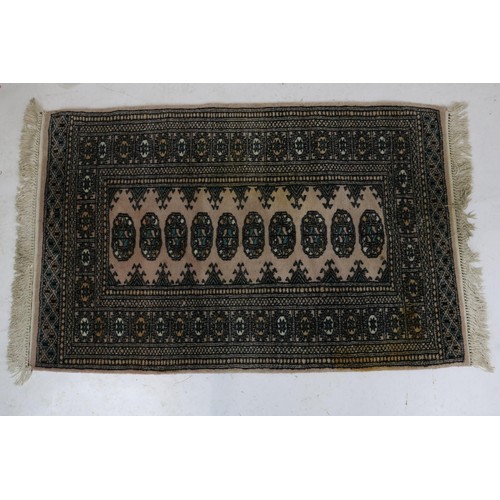 59 - An oriental rug with a beige ground measuring approx. 78x 124cm (Inspect)