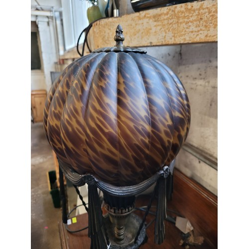 178 - An ornate lamp with brown flecked glass shade with metal frame with swag decoration. Measures approx... 