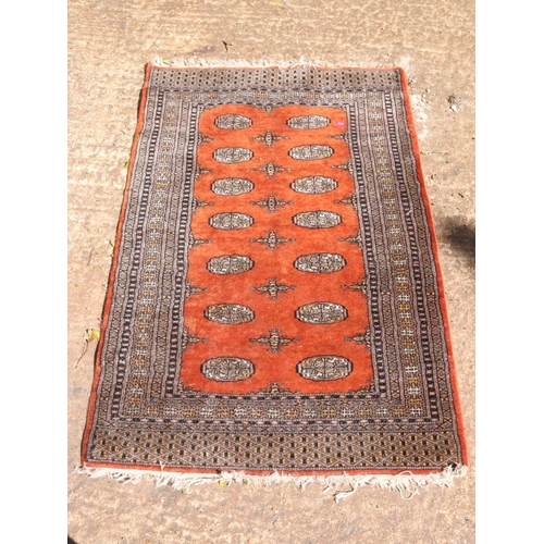 277 - A Bokhara rug with a rust coloured ground. Measuring approx. 149 x 96cm.