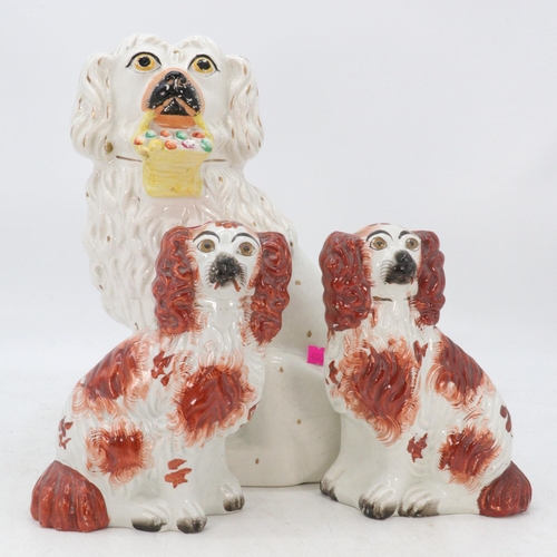 66 - Pair of Staffordshire spaniels together with a larger spaniel carrying a basket of flowers