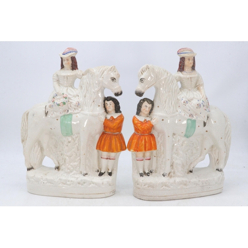 560 - Pair of Staffordshire figures depicting children on horseback (approx. height 34cm tall)