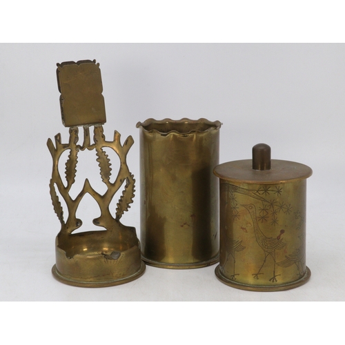 713 - Three pieces of brass trenchart to include a lidded pot, candle holder and another similar