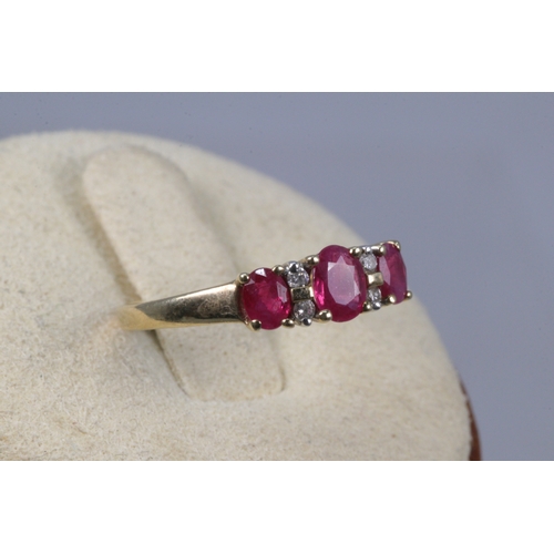 204 - 9ct gold three stone ruby ring with diamond spacers