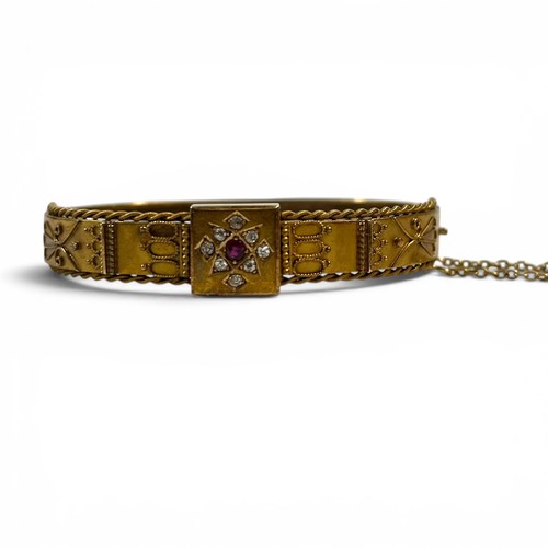 A diamond and ruby Victorian 15ct yellow gold Eiruscan Revivac Bangle, 17.4g, marked 15ct on snap clasp with twisted wire appliques, safety chain, in original box.
