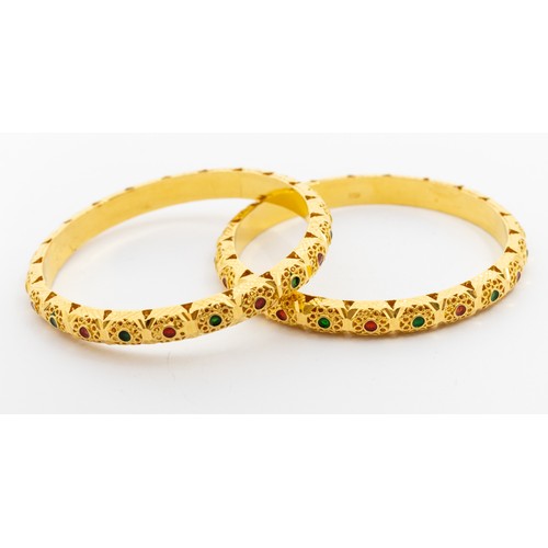 A pair of high carat gold and enamel matching bangles, comprising a D shaped form with pierced decoration and enamel green and red accents, width approx 7mm, internal diameter approx 62mm, unmarked xrf surface tested as 20ct at 8microns deep, possibly Indian origin, total gross weight approx 46.3gms 