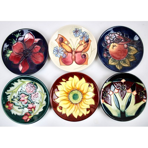 Six Moorcroft Pottery Pin Dishes of circular form comprising one "Orchid Trillium" pattern, one "Finches and Fruit" pattern, one  "Anemone" pattern, one "Inca Sunflower" pattern, one "Leicester" pattern and one "Butterfly" pattern, all impressed and painted marks to bases, all in Moorcroft boxes. (6)