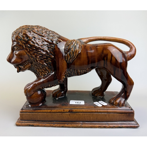 162 - Treacle glazed ceramic lion on plinth - Approx. W30cm H24cm D13cm