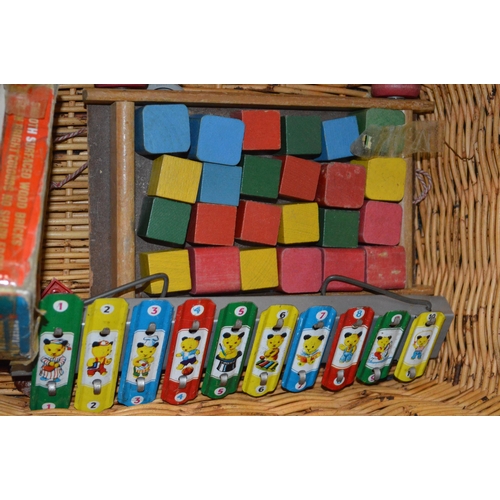 16 - A basket of vintage children's games including picture puzzle clock, Tri-ang colour spell bricks, a ... 