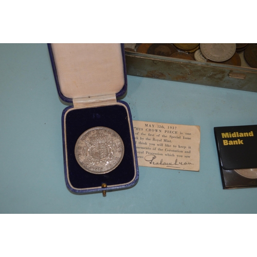 184 - A tin of various GB and world coins plus a few white metal brooches and an enameled 'Cyder' decanter... 