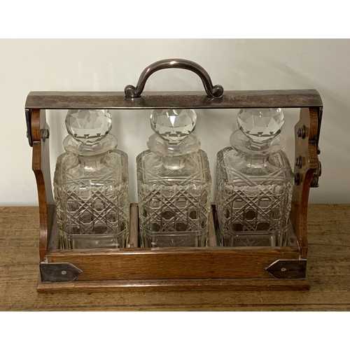 230 - Betjemanns patent oak framed three bottle tantalus with white metal mounts (some chipping to neck of... 