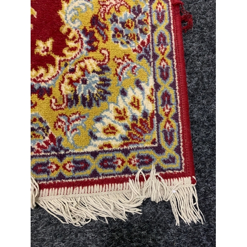 197 - A red ground Worsted Wool floor rug with fringe, approx. 67