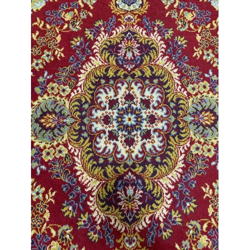 197 - A red ground Worsted Wool floor rug with fringe, approx. 67