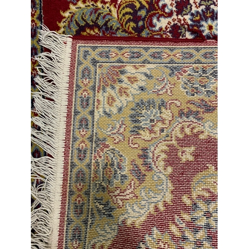 197 - A red ground Worsted Wool floor rug with fringe, approx. 67