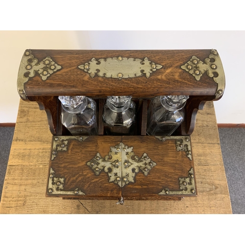 82 - A fine antique oak three bottle Tantalus with mirror back, formally silver plated mounts, Bramah loc... 