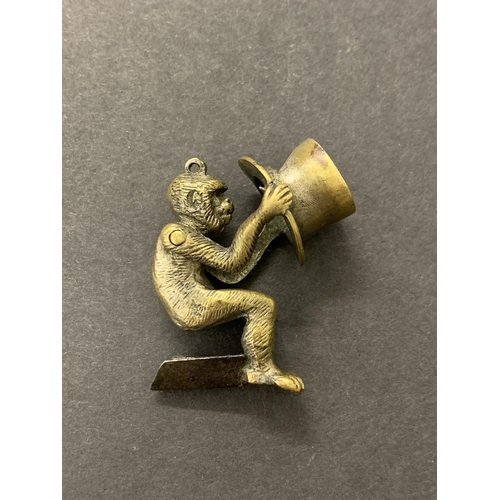 90 - A vintage brass monkey cigar piercer, the monkey sitting on a top hat articulated at the shoulders, ... 