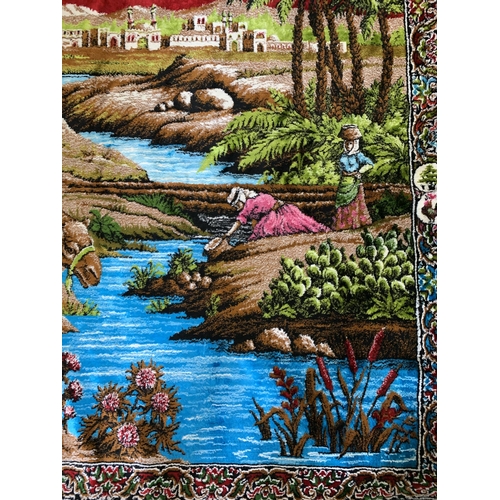 310 - A vintage brightly coloured floor rug with camels by a river, 71