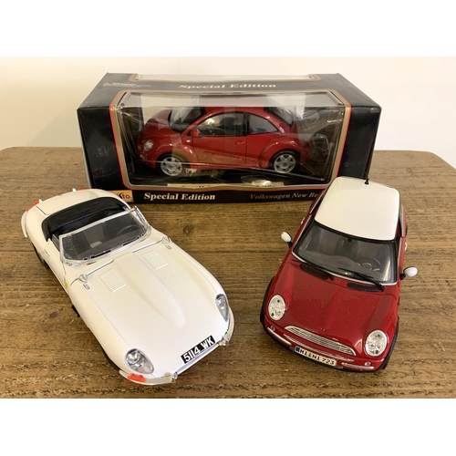 146 - A boxed Maisto 1/18 scale Volkswagen beetle together with two unboxed Jaguar E type and a Mini Coope... 