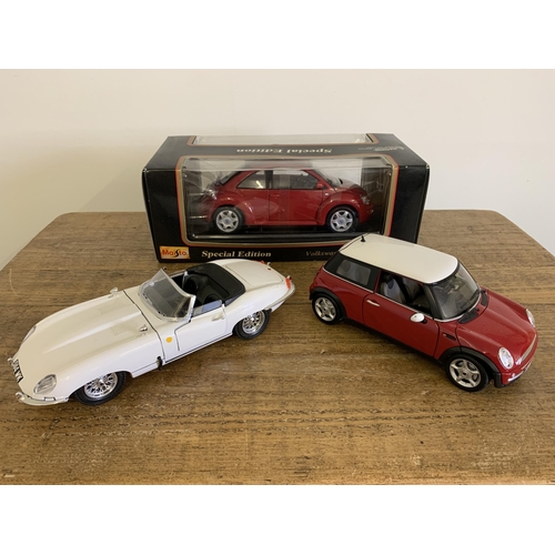 146 - A boxed Maisto 1/18 scale Volkswagen beetle together with two unboxed Jaguar E type and a Mini Coope... 