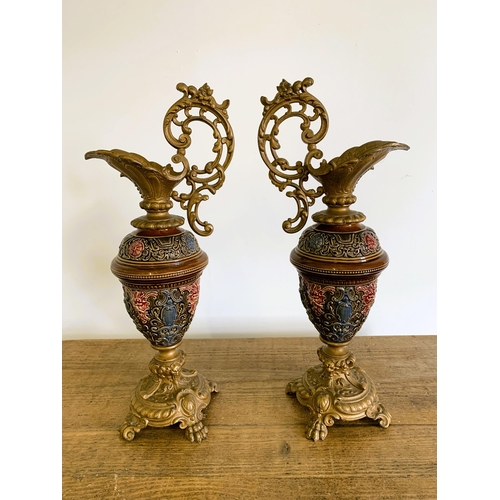 238 - A pair of late 19th Century Majolica and gilded spelter ewers, decorated with Bacchanalian faces to ... 