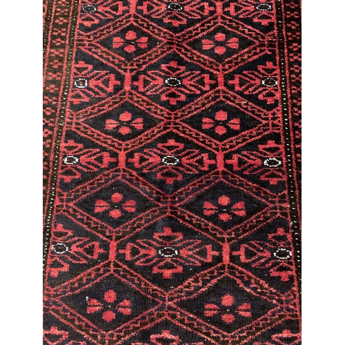 305 - A vintage red ground Belouch floor rug, 76