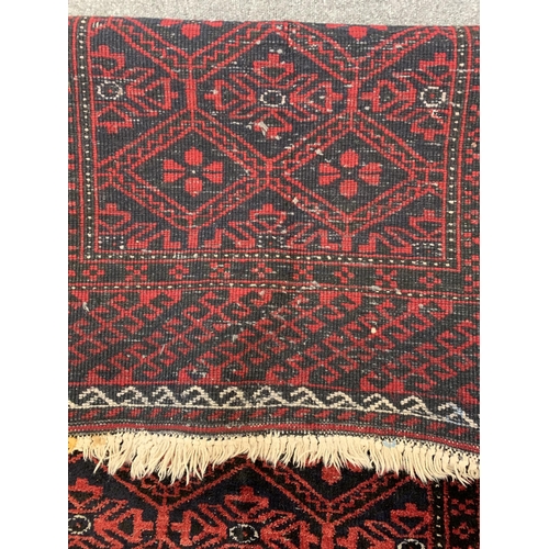 305 - A vintage red ground Belouch floor rug, 76