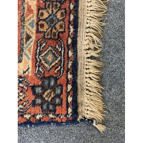 277 - A red ground multi coloured floor rug with fringe, 58