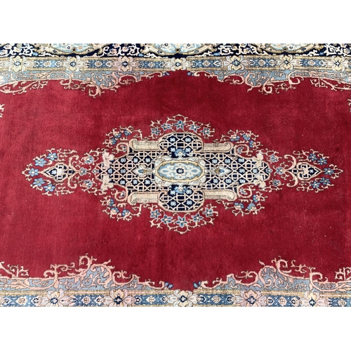 280 - A red ground and cream floor rug with tassels, 106