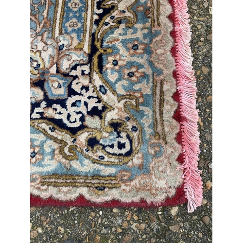 280 - A red ground and cream floor rug with tassels, 106