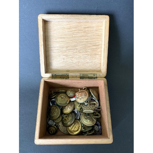 90 - A small wooden box with various military buttons and odd badges