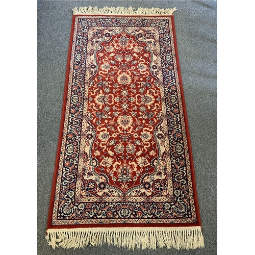 44 - A red ground floor rug with tassel ends, approx. 68