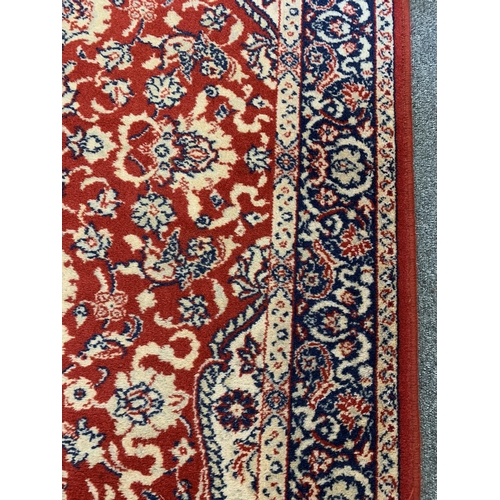 44 - A red ground floor rug with tassel ends, approx. 68