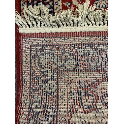 44 - A red ground floor rug with tassel ends, approx. 68