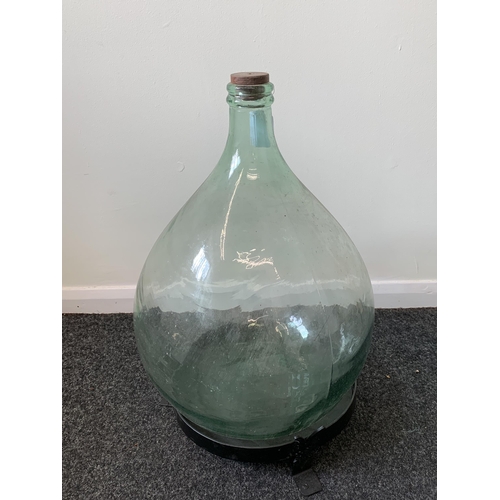 425 - A vintage glass carboy (green glass) with a wood and metal homemade stand, approx. 21