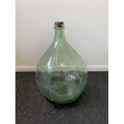 426 - A vintage glass carboy (green glass) with a wood and metal homemade stand, approx. 21