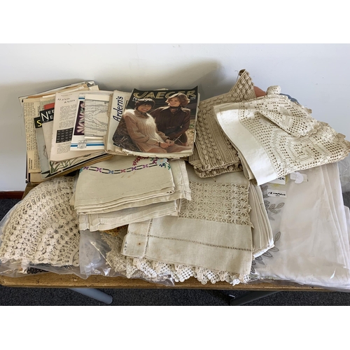 303 - Vintage linens and lace work including a hand embroidered table cloth and vintage knitting patterns