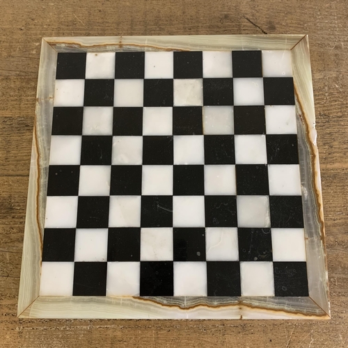 308 - A stone constructed chess board with black and white marble style tiles and onyx surround, 12