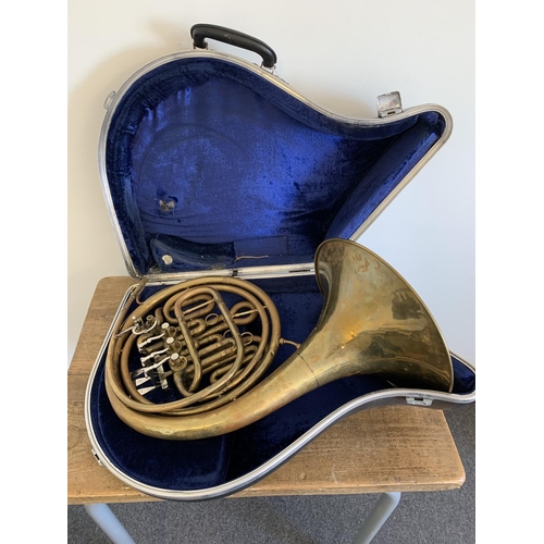 79 - A cased brass French horn (shows signs of much use, metal pitted, requires new mouthpiece, case as f... 